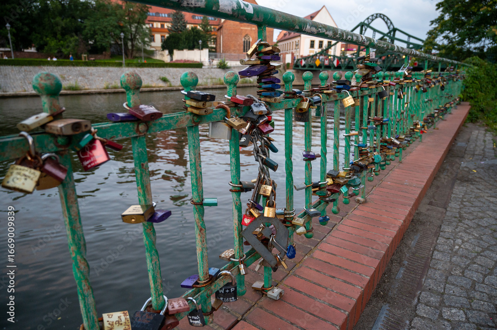 Fototapeta premium Love locks on a bridge railing along a city embankment at sunset. A symbol of eternal love, romance, and commitment. Travel and tourism concept