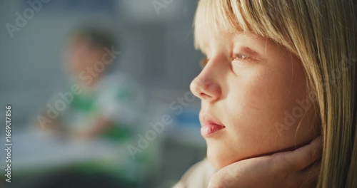 Close Up Shot of Thoughtful and Focused Young Girl Listening to Interesting Lecture from Teacher During Lesson, Sitting in Bright Classroom of Modern Primary School. Blurred Background with Children.