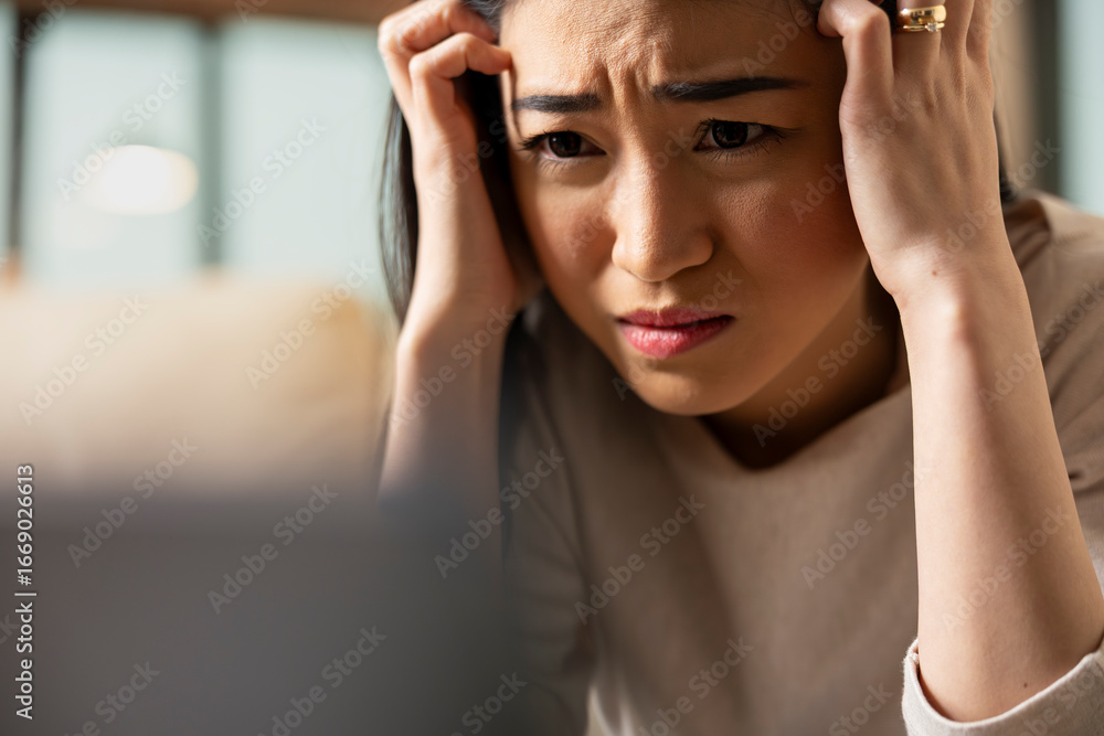 Fototapeta premium Worried self employed woman sits with head in hands, stressed about business project. Female manager overwhelmed by remote work demands, showing emotional fatigue and workplace anxiety at home.