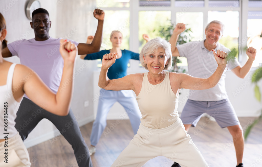 Fototapeta premium Dynamic mature attendees of dancing courses training Hip-hop dance poses in dancehall