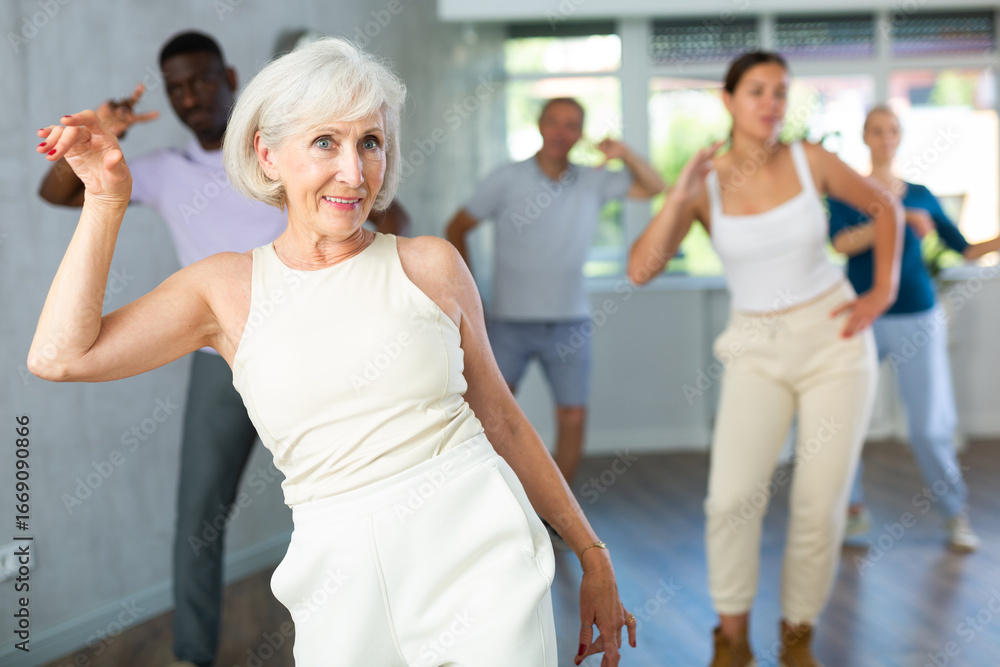 Fototapeta premium Active men and women of different ages practicing Rock 'n' Roll dance in training hall during dancing classes