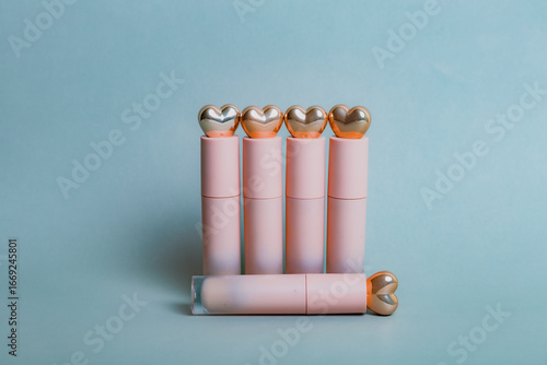 Bilde på lerret Row of pink lipsticks topped with gold hearts, perfectly aligned on a clean background