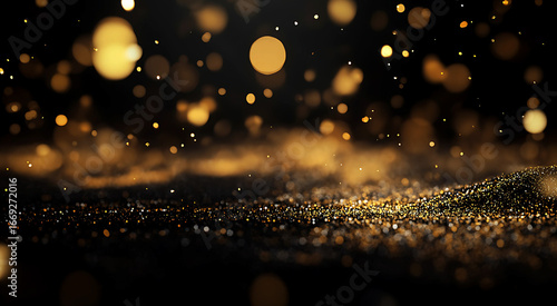 Particles of golden dust float and spread evenly with bokeh lights on a black background.