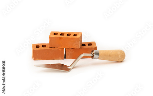 Construction trowel and three bricks on a white background. Building a miniature tower from bricks. Construction materials and tools