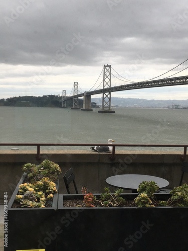 Bay Bridge Under a Cloudy Sky: A wide, scenic shot of the San Francisco Bay Bridge stretching across the water, with a grey, atmospheric sky overhead.