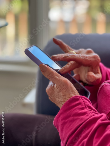 Closeup of elderly senior woman's hands using technology while scrolling down her mobile device. 