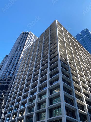 A Low-Angle View of a Modern Skyscraper: An upward-looking shot of a modern skyscraper in Chicago, with the elevated train tracks in the foreground, highlighting the city's unique transportation syste