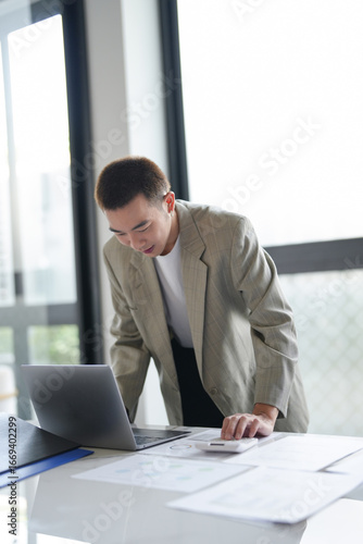 Attractive confident millennial Asian Business man using laptop computer and professional working investor start up project business planning in office.