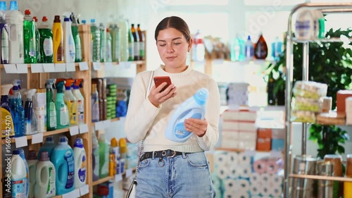 Woman is holding a phone in her hands and scanning the qr code of a home and kitchen cleaner. Customer pays a stain remover on an online app on a mobile. High quality 4k footage