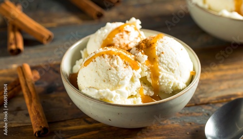 Creamy vanilla ice cream scoops are drizzled with a caramel sauce and sprinkled with cinnamon, creating a delightful dessert scene.