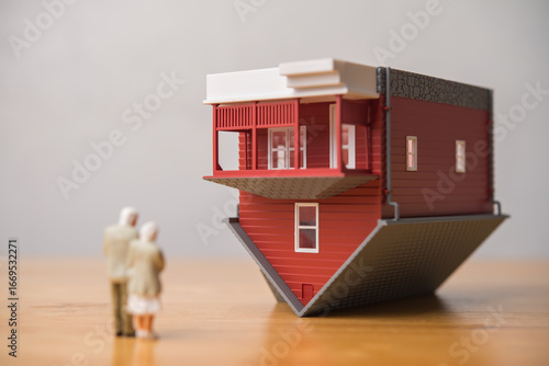 Photography Elderly couple looking at red house flipped over