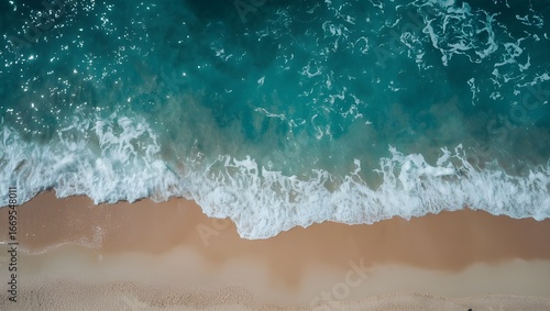 Stunning bird's eye view capturing the mesmerizing patterns of blue and green ocean water as gentle waves meet the warm, inviting sandy shoreline, embodying peace and natural beauty