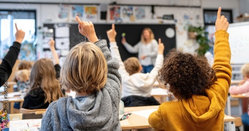 Classroom view children raise hands, teacher at board