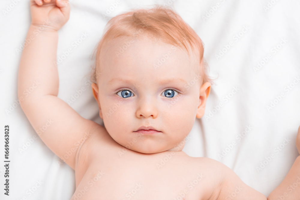 Portrait of a serious nine month old baby lying on his back and looking at the camera Portrait of a serious nine month old baby lying on his back and looking at the camera