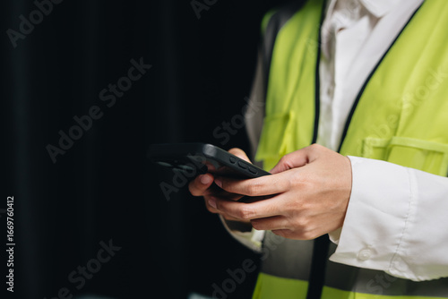 Construction Worker in Safety Vest Using Smartphone for Communication and Project Management