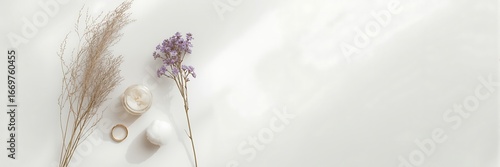 Overhead shot of cosmetic cream jar, cotton ball, golden ring, and dried flowers isolated on white background, showcasing a natural beauty concept