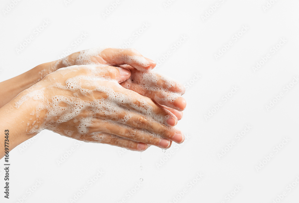 Fototapeta premium Close-up of hands washing with soap and water, covered in foam and bubbles on white background. Personal hygiene, health care, prevention of infection and virus protection.