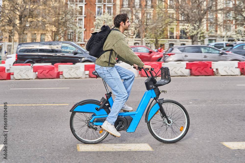 Obraz premium Student riding public bike sharing service in urban setting