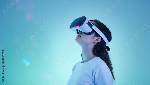 Metaverse technology concept, A young woman wearing a VR headset looks upwards, immersed in a digital world with a futuristic blue and green glow.