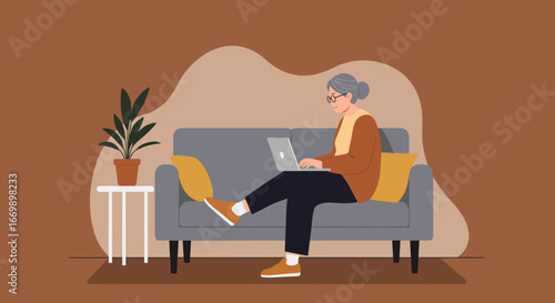 An elderly woman comfortably uses a laptop on a sofa at home, engaging in remote work or online learning, depicting digital literacy and independent senior lifestyle.