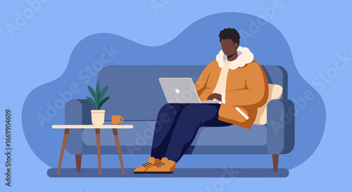 Young man comfortably working or studying on a laptop from his couch at home, embodying remote productivity and modern lifestyle.