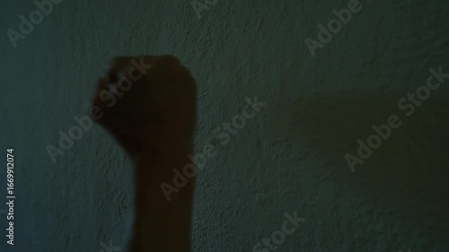 Close-up of a man's fist hitting a concrete wall in a dark room 4K