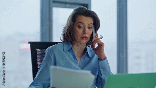 Nervous director talking smartphone holding bad report in office company closeup