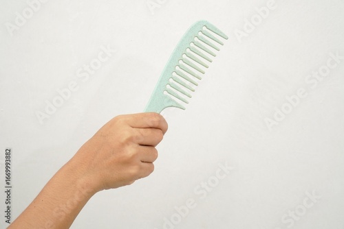 woman's hand holding a turquoise plastic comb isolated on white background