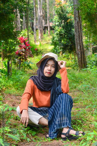 Young Asian Muslim woman hiking and camping in autumn forest, smiling at camera wearing Javanese ethnic clothes