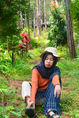Young Asian Muslim woman hiking and camping in autumn forest, smiling at camera wearing Javanese ethnic clothes