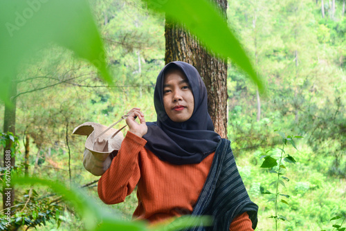 Young Asian Muslim woman hiking and camping in autumn forest, smiling at camera wearing Javanese ethnic clothes