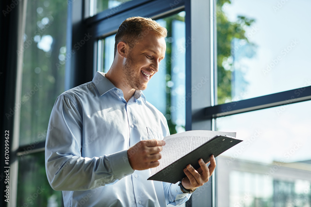 Fototapeta premium Young businessman focused on work while reviewing documents in a bright office environment