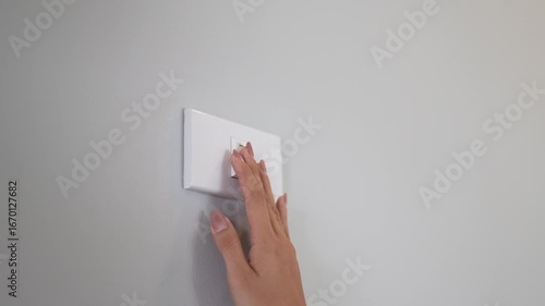 A person presses a light switch indoors, using their finger to control electricity, promoting energy saving, safety, and environmental conservation.
