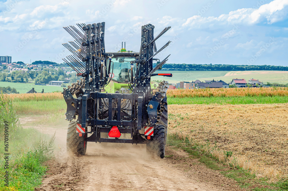 Fototapeta premium Tractor with cultivator driving along rural dirt road. Agricultural machinery, agriculture concept.