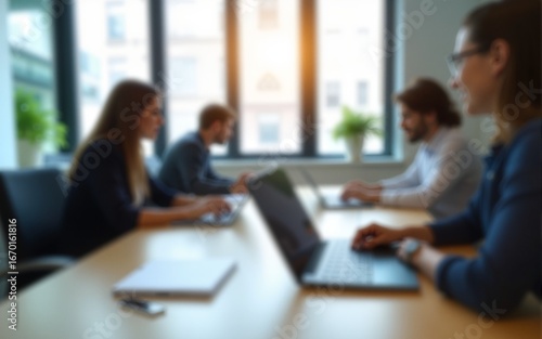 Blurred view of a modern office meeting room with people working on laptops, creating a professional and focused atmosphere. High quality