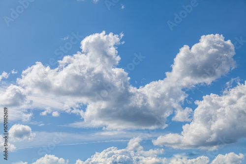 Fototapeta Naklejka Na Ścianę i Meble -  The sky is blue with a few clouds scattered throughout. The clouds are white and fluffy, giving the sky a peaceful and serene appearance