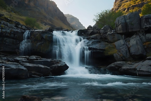 Serene Waterfall Flowing Over Rocky Cliffs in Mountain Valley