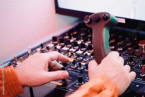 the hands of the operator controlling the robot manipulator on the robot control panel and on movement joystick.