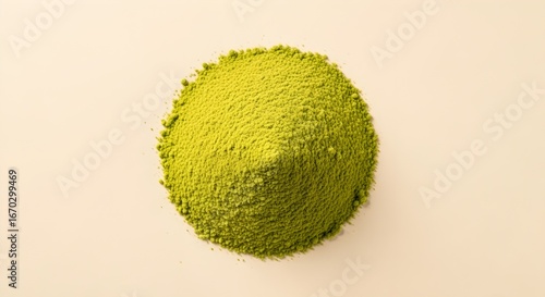 Top view of a bright green conical pile of matcha tea powder centrally placed on a clean light beige background, ready for beverage preparation.