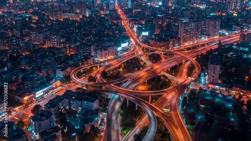 Dynamic night cityscape showcases illuminated highway interchange with flowing traffic lights creating motion blur