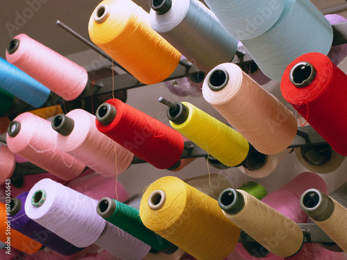 spools of threads of different colors on special hooks in factory