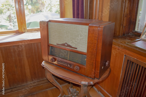 An antique radio sits on a wooden table by the window