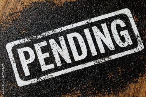 A close up of a pending stamp on a wooden surface with a black textured background around it