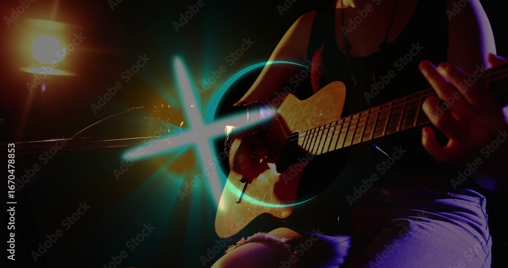 Naklejka premium Strumming guitarist in tank top on stage, with acoustic guitar, mic stand, spotlight, blue light