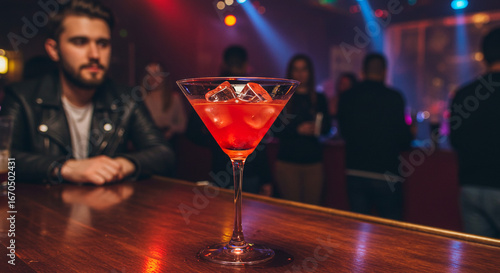 A young man at a luxury bar holds a red martini glass, celebrating with a classic cocktail