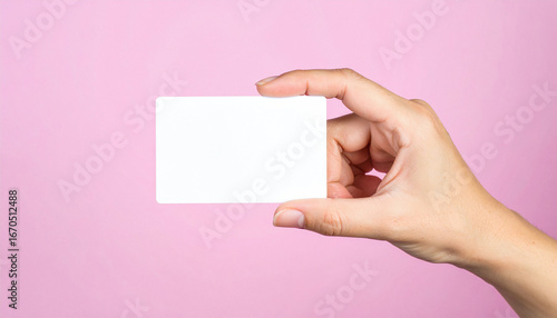 Hand holding blank business card on pink background
