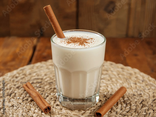 Glass of milky drink with cinnamon stick and powder