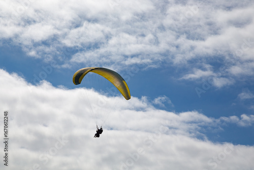 Persone su paracadute giallo e azzurro per parapendio
in cielo con nuvole