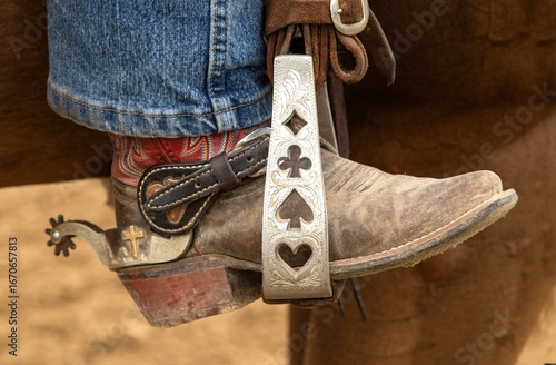 Canvastavla A closeup view of a custom designed silver stirrup with a colorful leather western style boot and a spur