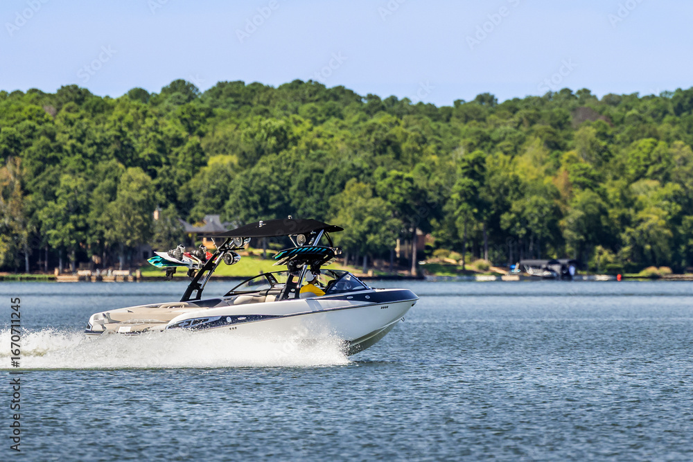 Fototapeta premium Boater on wakeboard wake ski boat enjoying summer day on freshwater lake.